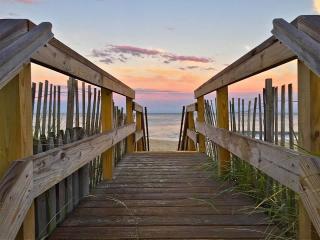 wooden path leading to the beach at sunset